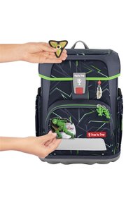 Rucksack aus dunkelblauem Stoff mit grünen Akzenten und geometrischen Mustern. Inklusive Gummiflicken: ein Ninja und ein dreieckiges Emblem.