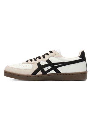 Low-top white sneaker with beige suede panels, black side stripes, black laces, and a brown rubber sole shown in side view.