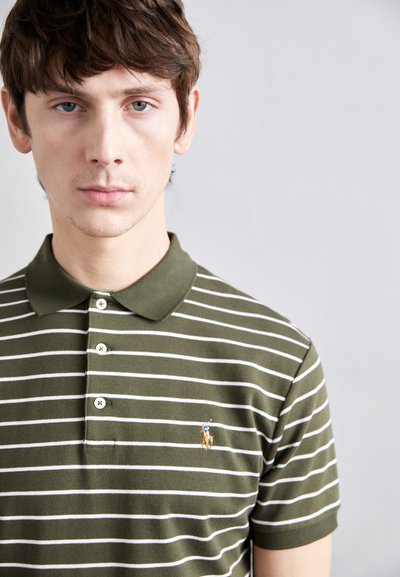 Zaļi un balti svītrots polo krekls ar divu pogu atloku un nelielu izšūtu polo spēlētāja logo uz krūtīm.