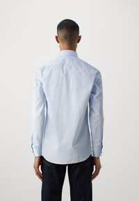 Hellblauses Langarmhemd mit abgerundetem Saum, glatter Textur, Knopfmanschetten mit blauen Akzenten und einem klassischen Kragen.