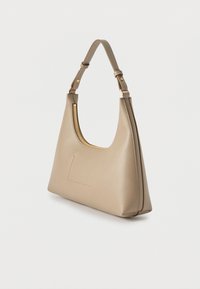 Μπεζ δερμάτινη γυναικεία τσάντα με έναν ρυθμιζόμενο ιμάντα, χρυσλό φερμουάρ και καθαρό, μινιμαλιστικό σχεδιασμό σε λευκό φόντο.