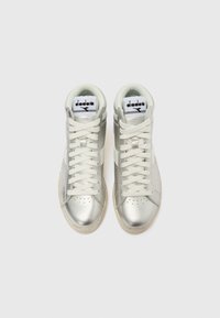 Ζευγάρι ασημί μεταλλικά ψηλά αθλητικά παπούτσια με λευκά κορδόνια και λογότυπο Diadora στη γλώσσα, εμφανιζόμενα από πάνω σε λευκό φόντο.