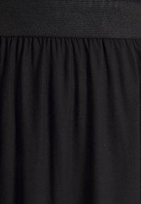 Zwarte elastische tailleband met zachte, gedrapeerde stof. Glad oppervlak met subtiele glans, dat een consistente zwarte kleur door het hele materiaal toont.