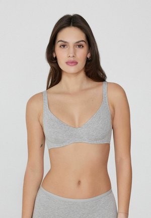 Soutien-gorge gris sans couture avec un décolleté en V plongeant, bretelles larges et une texture lisse. Design simple sans embellissements ni matériel.