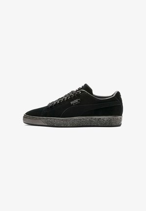 Baskets en suede noir avec une semelle en caoutchouc texturé, présentant un design à lacets et un logo PUMA sur le côté. Silhouette basse.