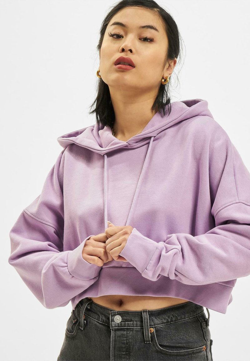Korte hoodie in lichtpaars, gemaakt van zachte stof. Kenmerkt brede mouwen, koordjes bij de halslijn en een losse pasvorm.