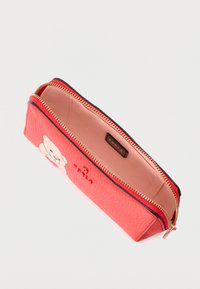 Piros texturált bőr erszény arany cipzárral, egyik oldalán medve mintával, belseje sima, bézs színű, logóval ellátott címkével.