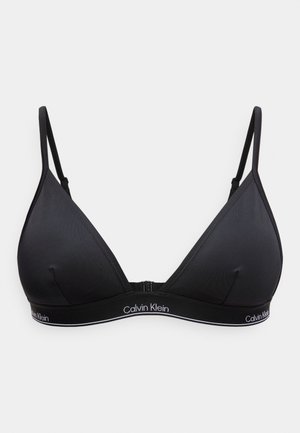 Svart Calvin Klein myk trekant-bh med justerbare tynne stropper og elastisk bånd med merke under koppene på ensfarget bakgrunn.