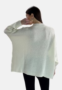 Maglione oversize color crema con scollatura a girocollo a coste e spalle scese, caratterizzato da una finitura testurizzata e un orlo asimmetrico.