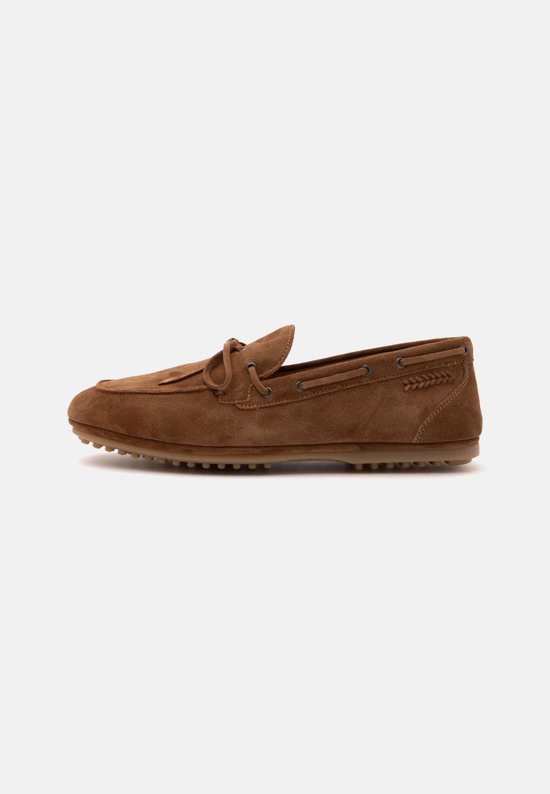 Mocassin en daim marron avec détail de lacet, semelle en caoutchouc avec crampons antidérapants et accent de couture sur un fond blanc uni.