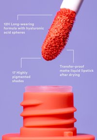 Matte flytande läppstift med ett texturerat, rött appliceringsverktyg. Behållaren är en orange tube med en vriddesign och genomskinligt lock.