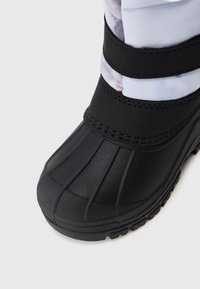 Černá vodotěsná bota s gumovou podrážkou, s drážkovaným designem, nastavitelnými popruhy a hladkým povrchem, sahající až k vršku z vzorované tkaniny.