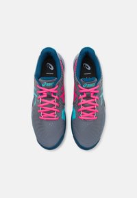 Scarpe sportive grigie con accenti rosa e teal, caratterizzate da una tomaia testurizzata, lacci rotondi e una suola decorata.
