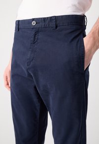 Marineblauwe chino's van lichtgewicht stof, met een knoopsluiting, zijzakken en een rechtlopende pasvorm met een minimale textuur.