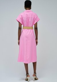 Rosa Hemdblusenkleid mit kurzen, gerollten Ärmeln, einem taillierten Gürtel und einem knielangen Saum. Glatter Stoff mit klassischem Kragen und gefaltetem Rückendetail.