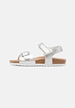 Silver metallic sandals with a buckle detail, cork footbed, adjustable strap, and white rubber outsole featuring a wavy pattern.