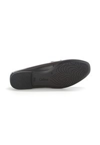 Black flat shoe with a smooth leather upper, a flexible rubber sole featuring a wave pattern, and embossed branding on the side.