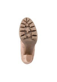 Suela de zapato de ante beige con un dibujo marcado que presenta estrías y formas de cruz. Punta redondeada y un tacón bajo con un acabado suave.