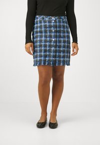Mini jupe à carreaux bleus avec un ourlet effiloché et une fermeture à boutons à l'avant. Confectionnée dans un tissu texturé, présentant un mélange de nuances claires et foncées.