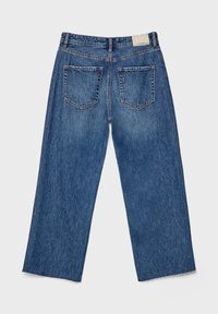 Jean en denim bleu à jambes larges vu de dos avec deux poches arrière et un ourlet brut en bas de chaque jambe.