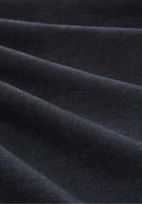 Svart texturerad tyg med en slät yta, som har en vågliknande drapering och subtila vävningsmönster, vilket framhäver dess djup och rikedom.