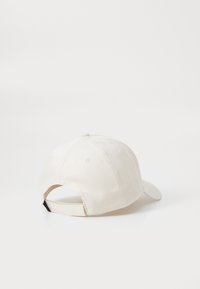 Beige bomulds-baseballcap med buet skygge, justerbar rem bagpå og seks ventilationshuller på toppen. Struktureret stof.
