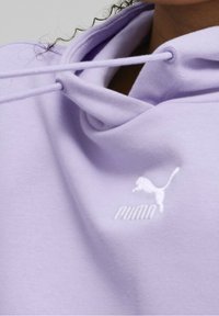 Sweat à capuche violet clair avec cordon de serrage, texture douce et logo Puma blanc brodé sur la poitrine.