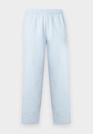 Pantalon de survêtement Adidas bleu clair avec taille élastique et poches latérales, arborant un petit logo Adidas blanc sur la cuisse gauche.