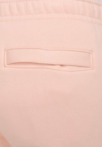 Pantalones de chándal rosa claro con textura suave y un bolsillo plano en la parte trasera. La cinturilla tiene elastano para mayor comodidad.