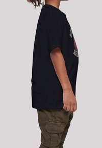 Sort kortermet T-shirt bæres med olivengrønne cargo-bukser, med et grafisk print på forsiden og en afslappet pasform.