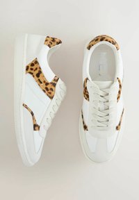 White sneakers with a textured leather upper and leopard print accents on the sides. Features flat laces and a thick rubber sole.