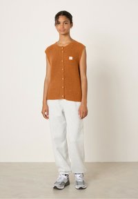 Bruine korte mouwen cardigan met een textuur brei en knoopsluiting, gecombineerd met grijze sweatpants en sneakers. Klein logo op de borst.
