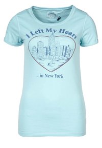 Camiseta de color azul claro con un horizonte de Nueva York en forma de corazón y el texto "Dejé mi corazón...en Nueva York" impreso en la parte frontal.