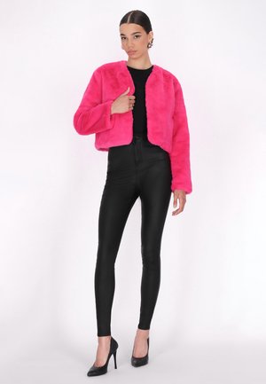 Felroze nepbont cropped jack, lange mouwen, ronde halslijn, gecombineerd met hoge zwarte neplederen leggings en zwarte hakken.