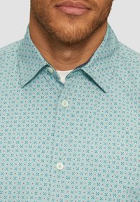 Lichtblauw overhemd met een geometrisch patroon van kleine rode en marineblauwe kruisen, voorzien van een klassieke kraag en lichte knopen.