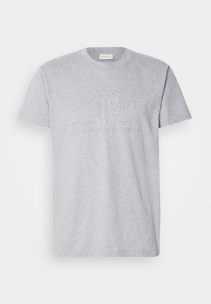 T-shirt en coton gris avec un col rond, des manches courtes et un design de logo en relief au centre. Texture douce. Coupe classique.