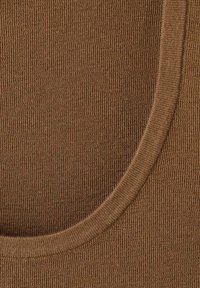 Tejido de color marrón con canalé y cuello redondo ajustado. La textura es suave con un ligero aspecto elástico.