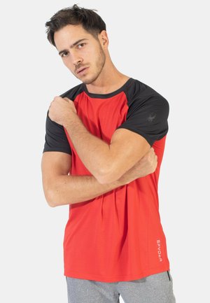 Rotes Sportshirt mit einem schwarzen gerippten Kragen und Ärmeln. Hat ein strukturiertes Muster und ein kleines Logo auf dem linken Ärmel.