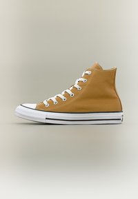 Καφέ αθλητικό παπούτσι ψηλού πάτου από καμβά με λευκά κορδόνια, λευκή λαστιχένια μύτη και λευκή σόλα με μαύρες ρίγες, απεικονισμένο σε πλάγια όψη.