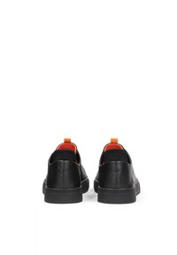 Black leather shoes with a low profile, featuring a textured upper, orange accent pull tabs, and a black rubber sole.