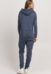 Marineblå hettegenser i myk, strukturert stoff. Har avsmalnende ben, ribbestrikkede mansjetter og kengurulomme. Rent, enkelt design.