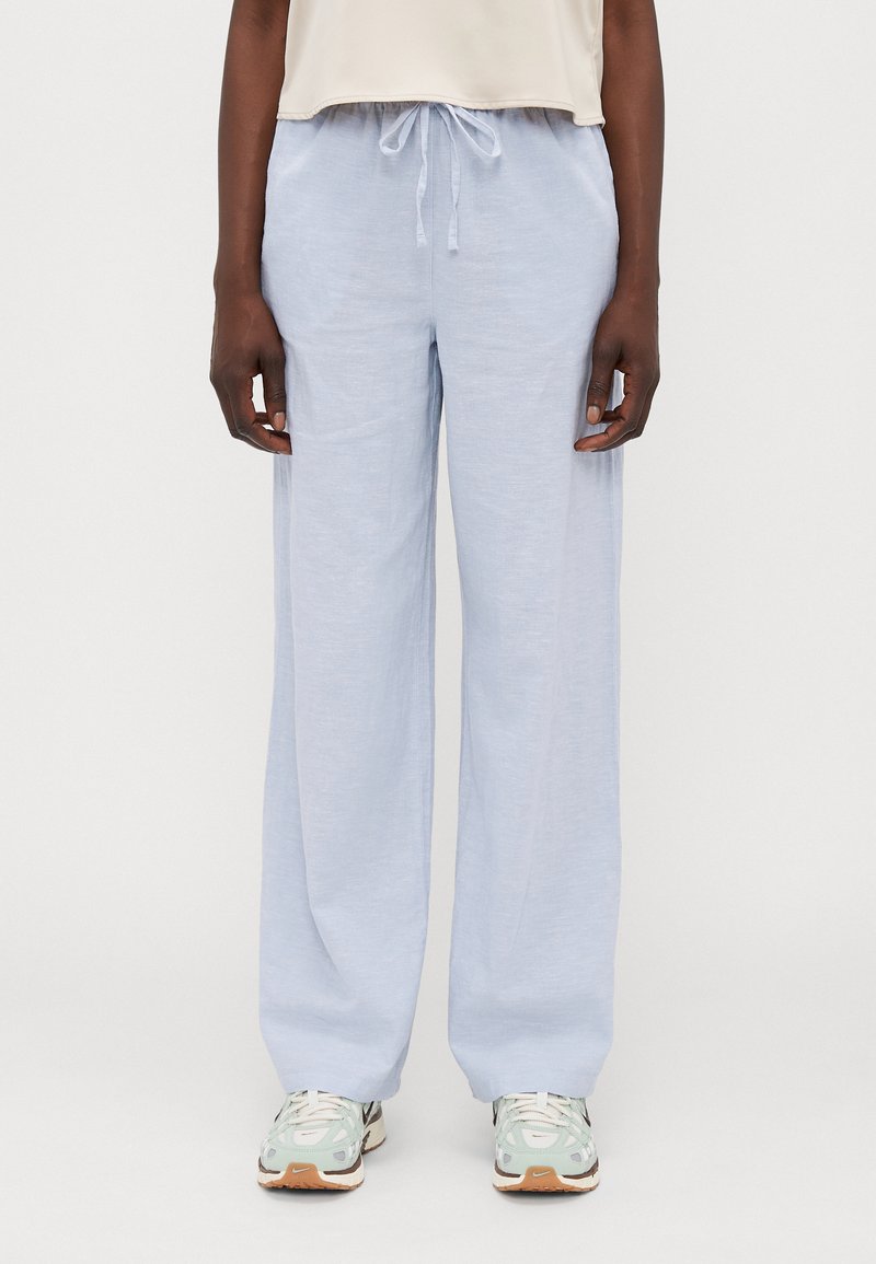 Light blue, loose-fitting, lightweight pants with an elastic waistband and drawstring. Paired with white and mint athletic shoes.