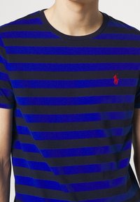 Blau- und navygestreiftes T-Shirt aus Baumwolle mit Rundhalsausschnitt und kleinem roten Logo auf der Brust.