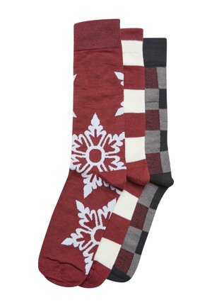 Drei Paar Socken: ein rotes Paar mit weißem Schneeflockenmuster, ein gestreiftes rot und cremefarbenes Paar sowie ein graues Paar mit schwarzem und rotem Karomuster.