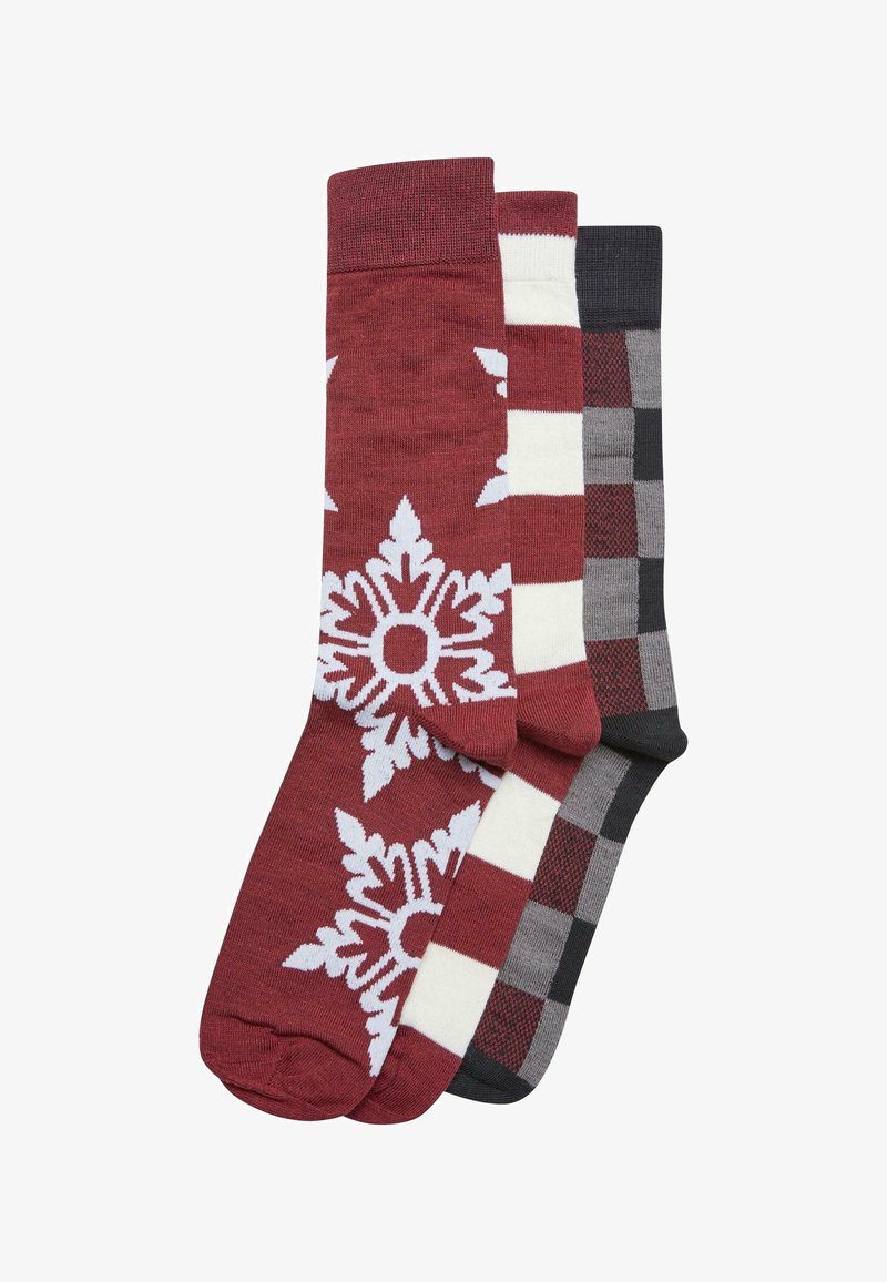 Drei Paar Socken: ein rotes Paar mit weißem Schneeflockenmuster, ein gestreiftes rot und cremefarbenes Paar sowie ein graues Paar mit schwarzem und rotem Karomuster.