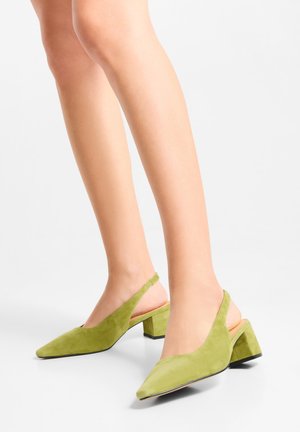Green suede slingback heels with a pointed toe and block heel. Features a curved cutout design and a smooth texture.