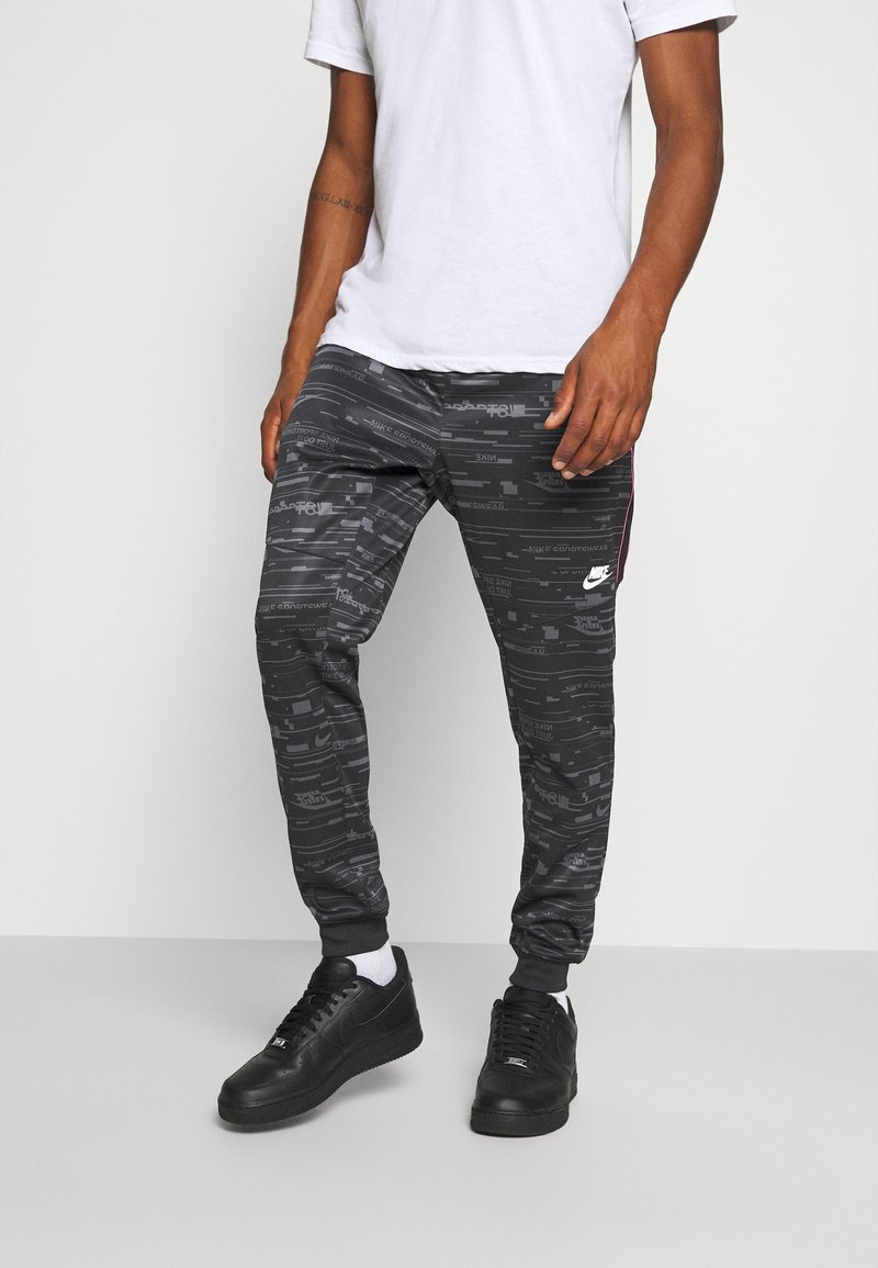 Svarta joggingsbyxor med en texturerad grafisk tryck, som har en snug passform, elastisk midja och kontrasterande sidostråk. Matcher med svarta sneakers.