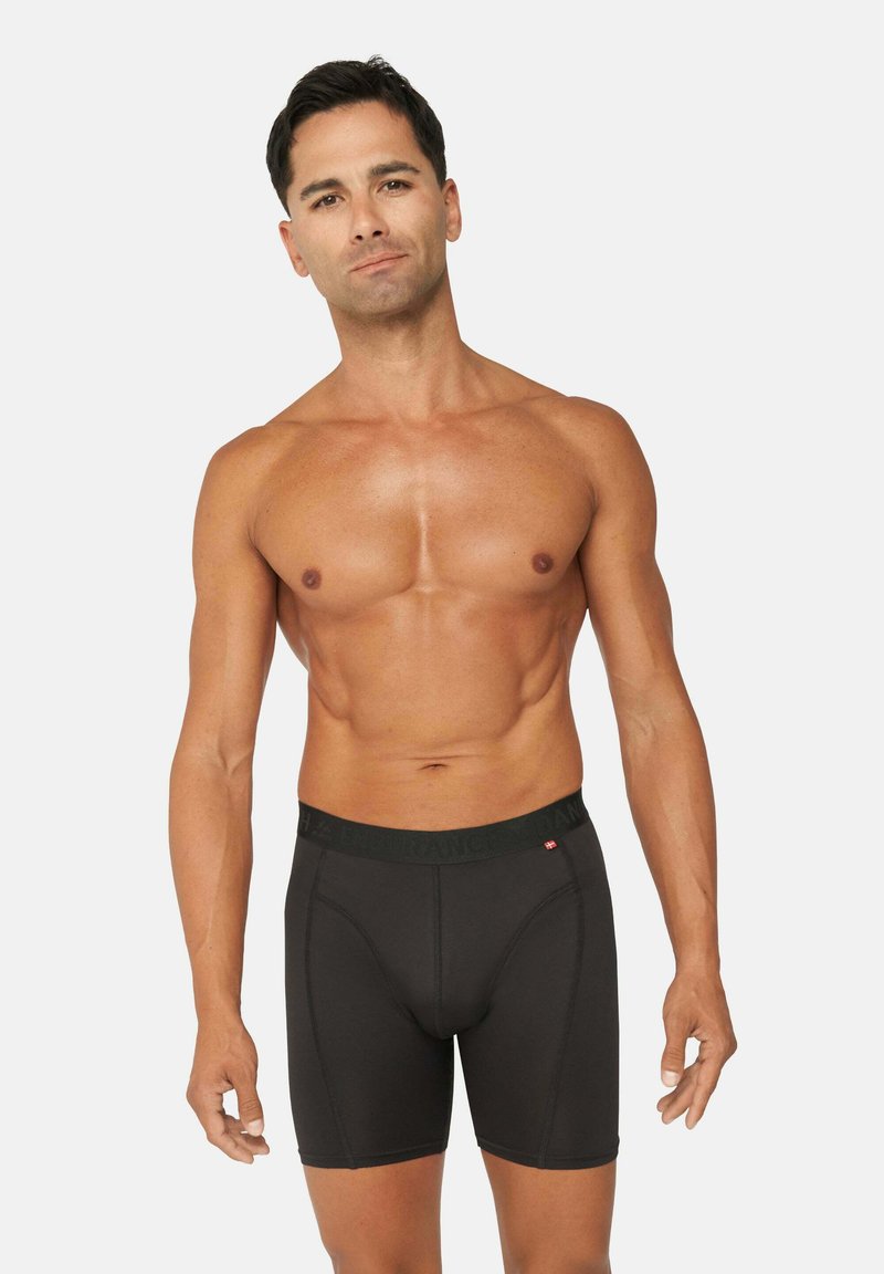 Zwarte boxershorts met een brede elastische tailleband, gekenmerkt door een gladde stofstructuur en een aansluitend ontwerp dat dekking tot halverwege de dijen biedt.