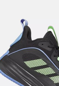 Basket noire avec des accents bleus, un motif rayé vert, une languette au talon et une semelle épaisse portant l'inscription « Lightmotion ».