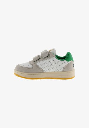 Sneaker bianca con inserti in camoscio grigio, dettaglio verde sul tallone e design traforato. Presenta due cinturini regolabili in Velcro e una suola gialla texturizzata.